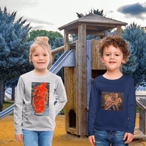 Dos niños posan sonrientes en un parque frente a una estructura de juegos de madera. La niña a la izquierda viste un buzo gris de manga larga con una ilustración vertical de ángeles entrelazados con rosas anaranjadas. El niño a la derecha viste un buzo azul marino con una obra impresa que muestra a dos ángeles en una composición clásica. El entorno es natural con árboles y un cielo nublado, resaltando el uso cotidiano del arte.
